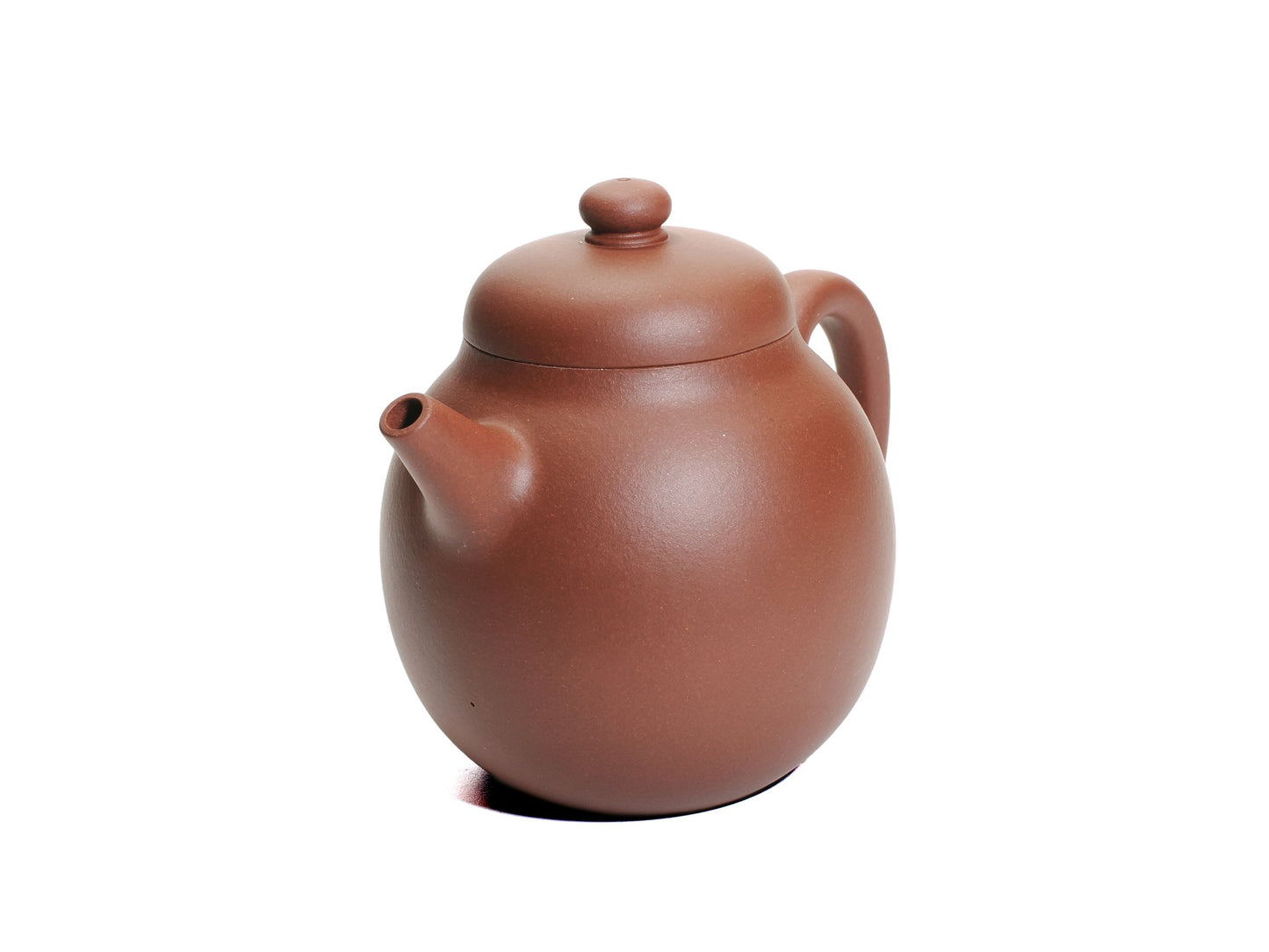 Angled front‑right view of the Ming‑style Da Long Dan teapot displaying its rounded body, short spout and domed lid knob in reddish clay.