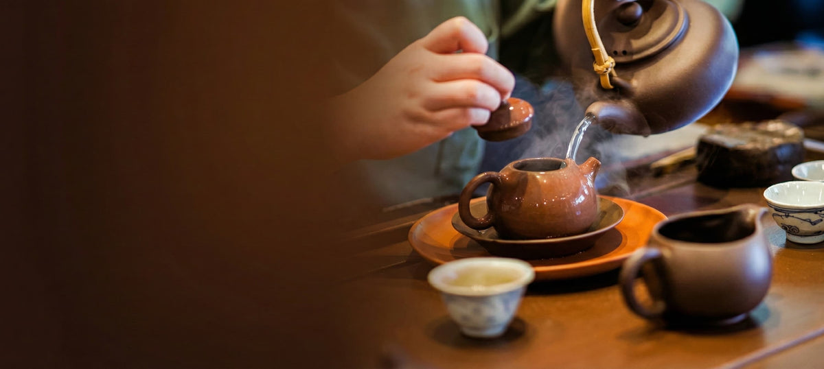 Traditional Yixing purple clay teapot pouring steaming tea during a Gongfu tea ceremony, celebrating Cha Zhi Ji's 30th Anniversary and 12.12 Sale.