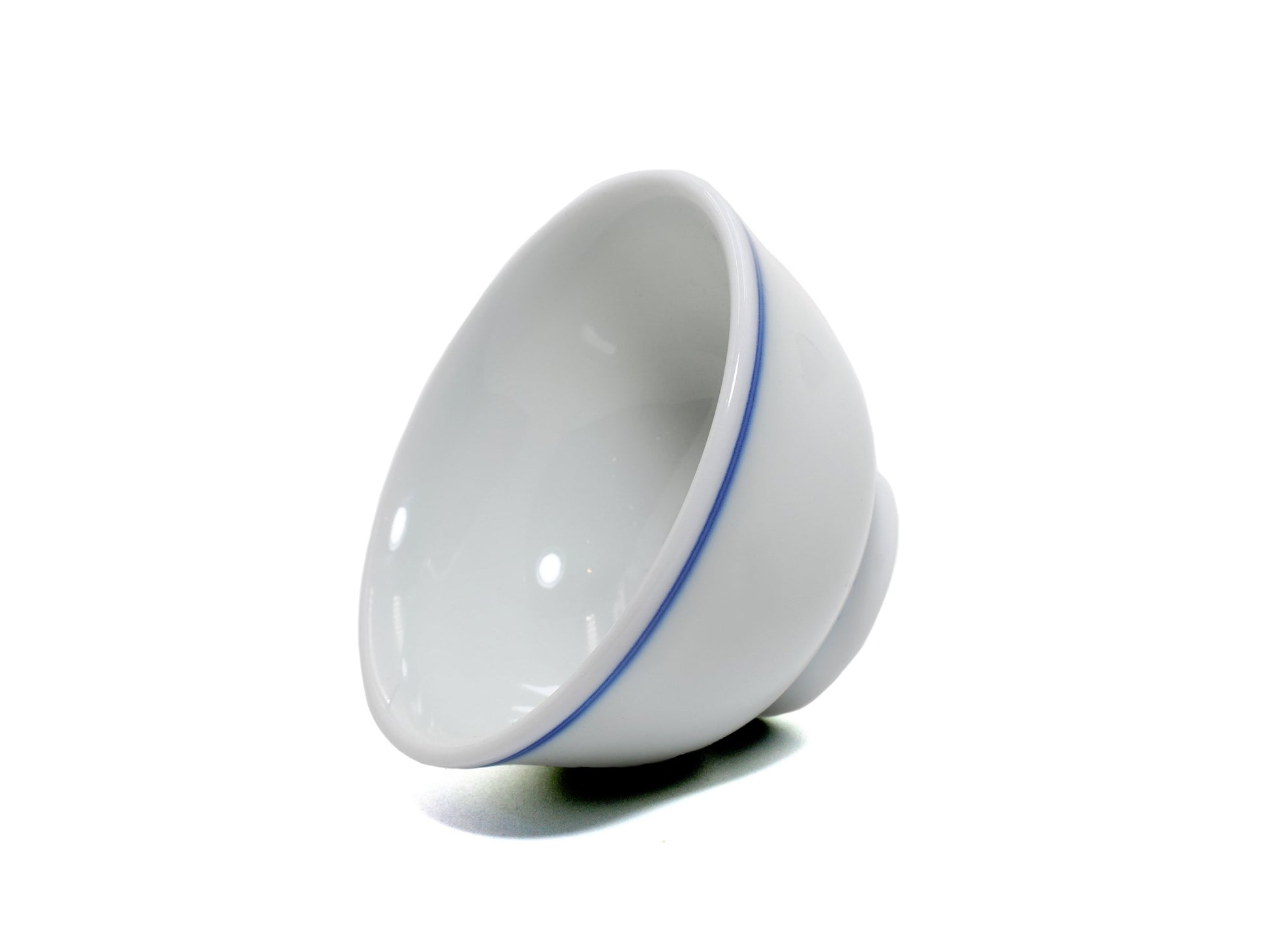 Porcelain teacup tilted to show interior glaze and blue rim line