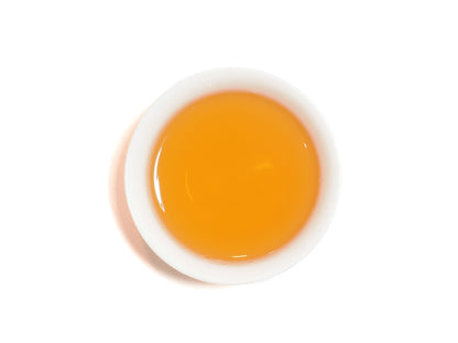 Bright orange-red liquor of Yixing Gong Hong black tea in a white cup
